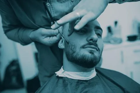 Master makes beards correction in barbershop salon. Close up photo. Stock Photos