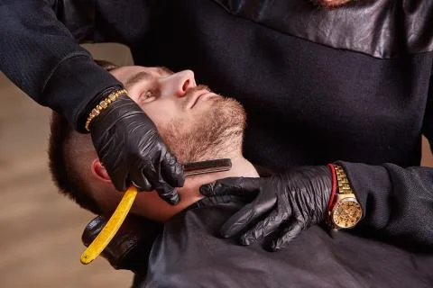 Master makes beards correction with shaver in barbershop salon. Close up photo. Stock Photos