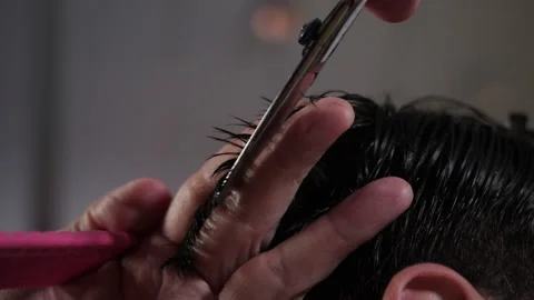 The master makes a cut with scissors and and a pink comb client to a man Stock Footage 147908154