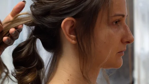 A master makes an evening hairstyle for a model with long dark-blond hair 動画素材 127500879