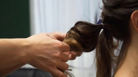 A master makes an evening hairstyle for a model with long dark-blond hair 動画素材 127502500