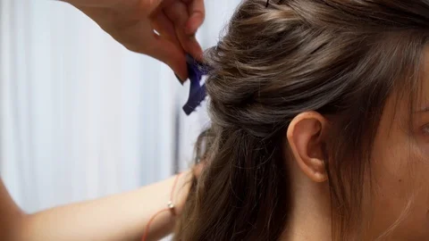 A master makes an evening hairstyle for a model with long dark-blond hair Stock Footage 127502627