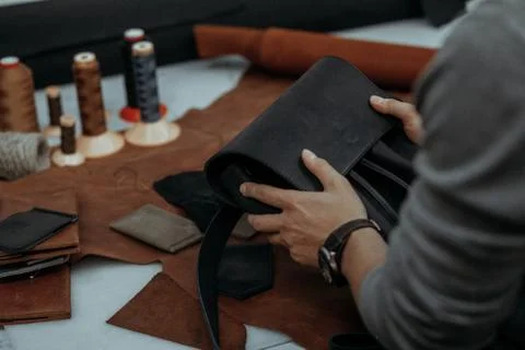 The master makes a leather bag. A close up, a product from skin in hands. Stock Photos