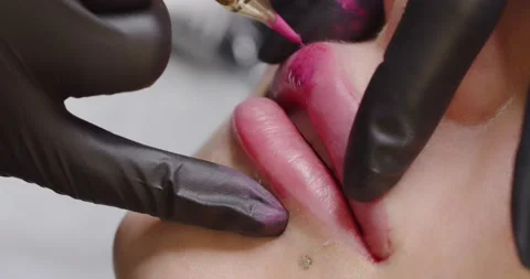 The master makes lip tattoo for a client in a beauty salon with a special device Stock Footage 171773784