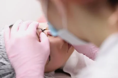 Master makes permanent makeup for eyelids of client in salon Stock Photos