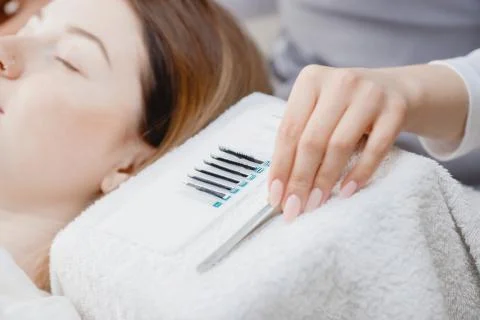 Master making fake long lash Eyelash extension procedure with tweezers for woman Stock Photos