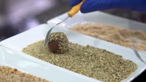 Master making a truffle, covering chocolate ball with crushed pumpkin seeds Stock Footage 88947255