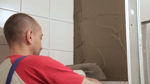 Master man applies glue on wall before laying tiles indoors. Stock Footage 78158762