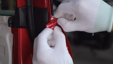 Master man is gluing protective vinyl tape on edge of door of car Stock Footage 121417834