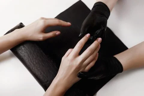 Master of manicure in black gloves, makes massage moisturizing cream client. Stock Photos