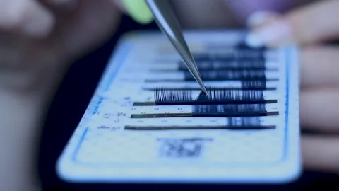 Master with manicure is choosing false lashes in a set with tweezers, close-up Stock Footage 150400481