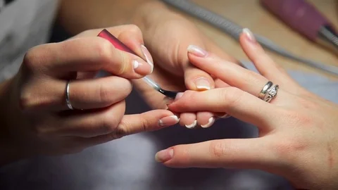 Master of manicure covers woman's nails by transparent nail polish, woman comes Stock Footage