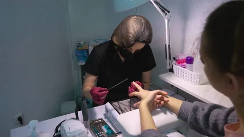 The master of manicure with a nail file makes a neat shape of nails of client Stock Footage 146488712