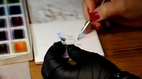 The master of the manicure puts the drawing in blue on the base with rhinestones Video stock 86986950