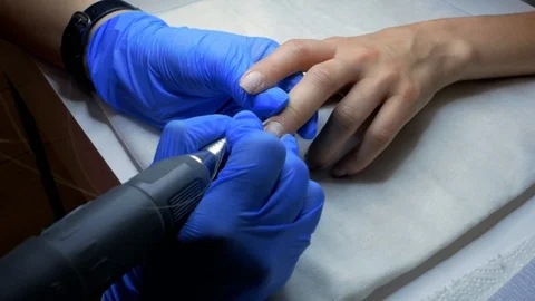 Master of manicure removes cuticles on nails. manicurist makes hardware manicure Stock Footage 114314483