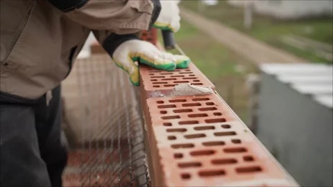 A master mason is laying a red brick wall. The master at the construction site Video stock 141287459