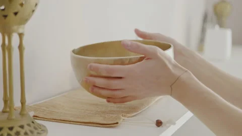 Master in massage parlor takes singing bowl for sound therapy from shelf. Stock Footage 197674734