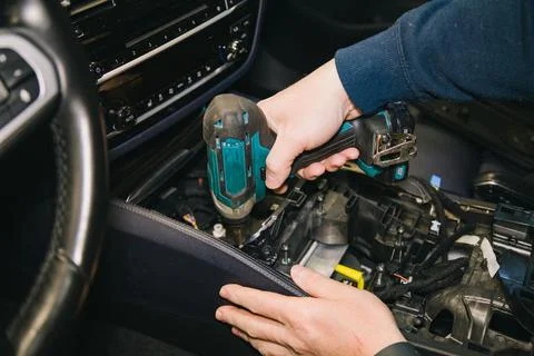 A master mechanic disassembles the car interior using a power screwdriver Stock Photos