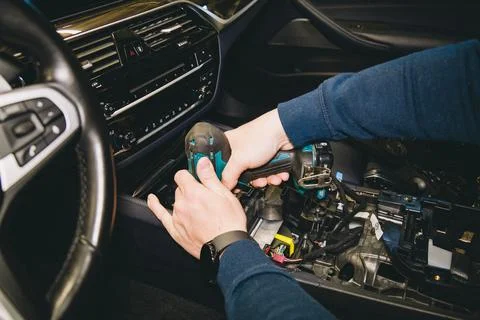 A master mechanic disassembles the car interior using a power screwdriver Stock Photos