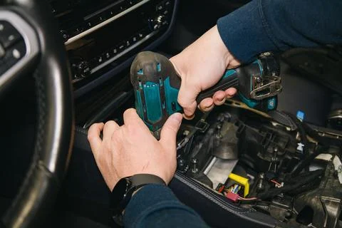 A master mechanic disassembles the car interior using a power screwdriver Stock Photos