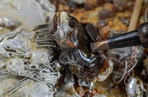 The master melts the tin with a soldering iron Stock Photos