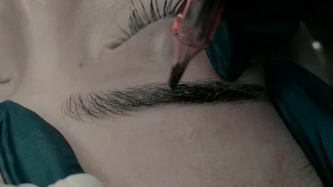 Master of microblading at work makes a pigment on the eyebrow. close up Video stock 223157528