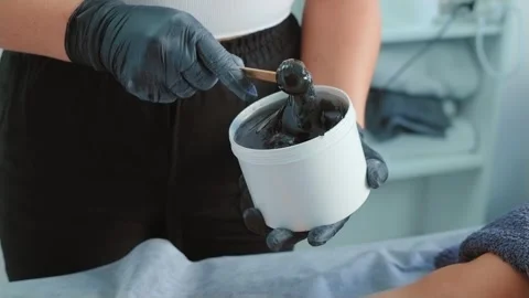 Master mixes heating wax with wooden spatula before depilation procedure close Stock Footage 252196418
