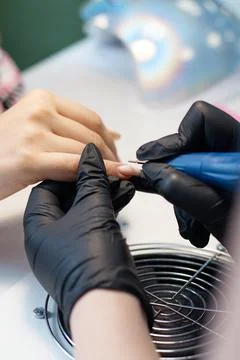 The master of nail service does a manicure, covers with varnish and increases Stock Photos