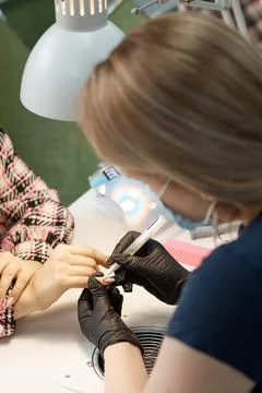 The master of nail service does a manicure, covers with varnish and increases Stock Photos