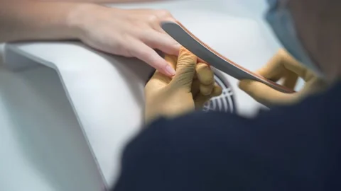 The master of the nail service sharpens the client's nails with a nail file 库存影片 165222599
