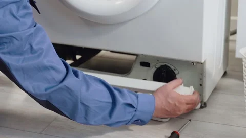 The master opens the lid of the washing machine's drain pump close-up, cleaning Stock-Footage 133866934
