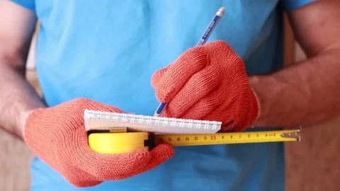 Master in orange gloves holding tape-line and writing 스톡 동영상 83949974