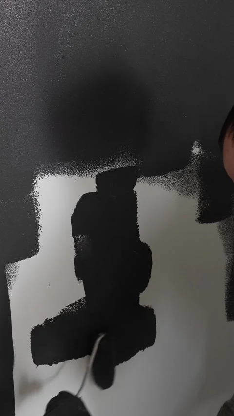 Master painter builder paints a concealed door in dark gray with a roller Video stock 317409524