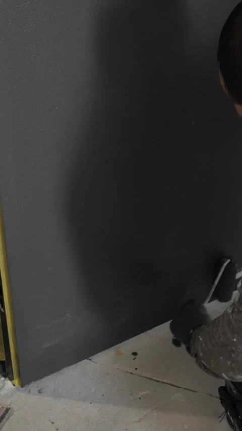 Master painter builder paints a concealed door in dark gray with a roller Video stock 317409530