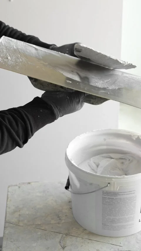 Master painter builder takes a spatula and applies plaster from a bucket Stock Footage 317409500