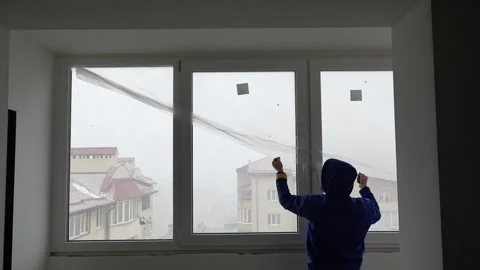 Master painter covers a window with film before renovating an apartment Stock-Footage 317394815