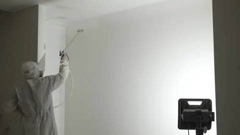A master painter  paints and primes a wall with an airless paint sprayer Stock Footage 317394986