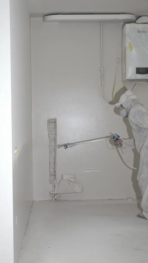 A master painter paints and primes a wall with an airless paint sprayer Video stock 317395459
