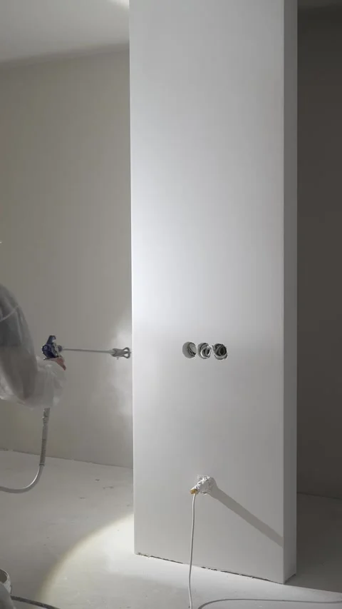 A master painter paints and primes a wall with an airless paint sprayer Video stock 317395559