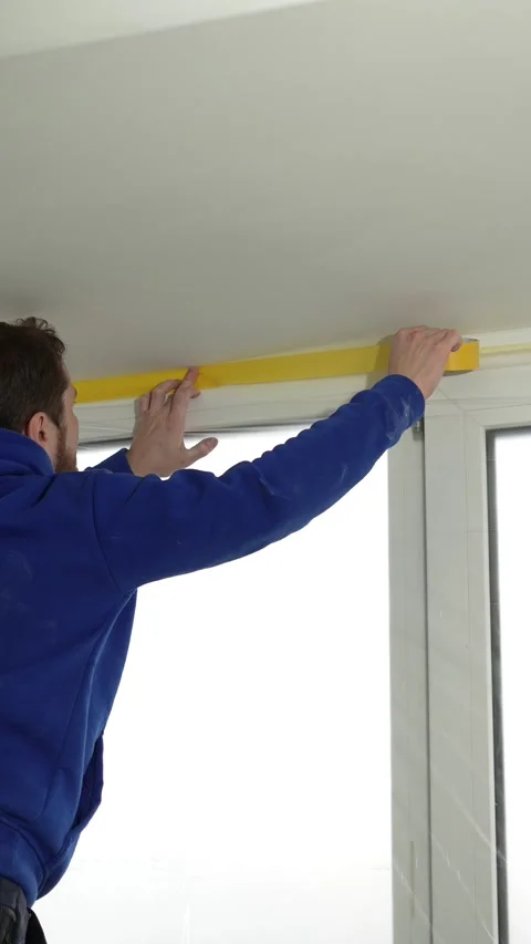 Master painter seals a window with protective film before renovating Stock Footage 317395172