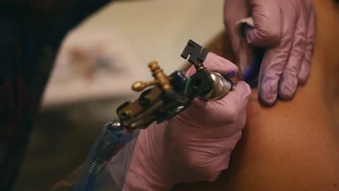 The master paints a tattoo with a drawing of death on the shoulder of a man Stock Footage 80919642