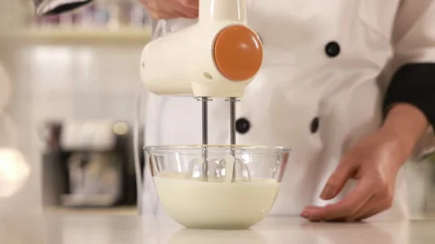 Master pastry chef hand whipping raw egg whites with sprinkles sugar with Stock Footage 339380289