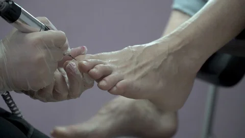 Master of the pedicure removes cuticles on the nails in the beauty salon Stock-Footage 87464808