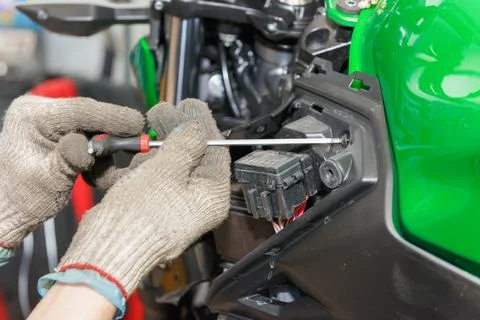 The master performs maintenance on the motorcycle. Removing the fuel tank. Stock Photos
