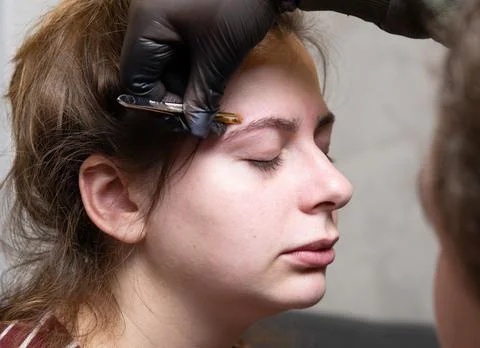 The master of permanent make-up prepares the client's eyebrows for the proced Stock-Fotos