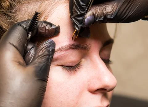 The master of permanent make-up prepares the client's eyebrows for the proced Stock Photos