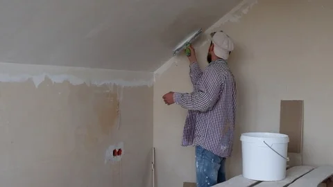 Master in a plaid shirt applying putty on putty knife Stock Footage 128817908