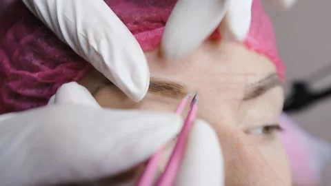 The master plucked the eyebrows of the client with thick brows in beauty salon Stock Footage 149200977