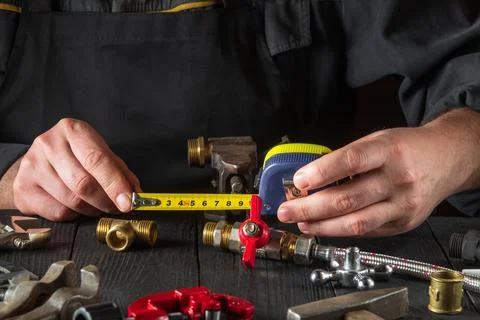 Master plumber measures the distance using a tape measure. Stock Photos