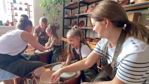 Master potter teaches children and their moms to make a clay jug Stock Footage 277790014
